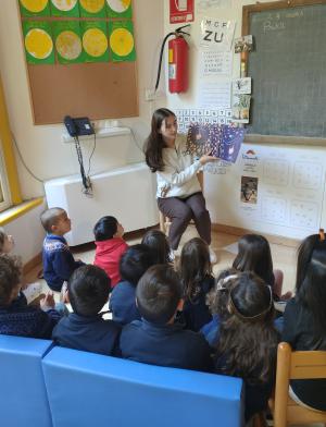 A student in her teaching internship reads a picture book to a group of school children.