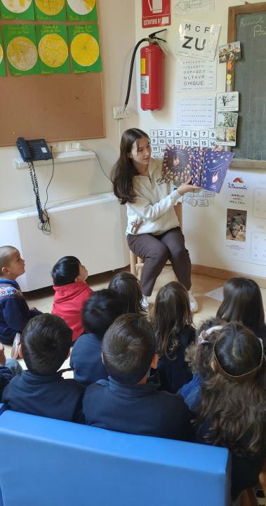 A student in her teaching internship reads a picture book to a group of school children.