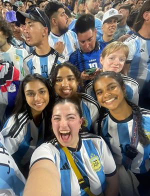 a group of students in Argentina futbol jersey's in a crowd